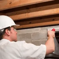 Termite inspection technician checking a basement wall and framing for termite activity in Chattanooga, TN